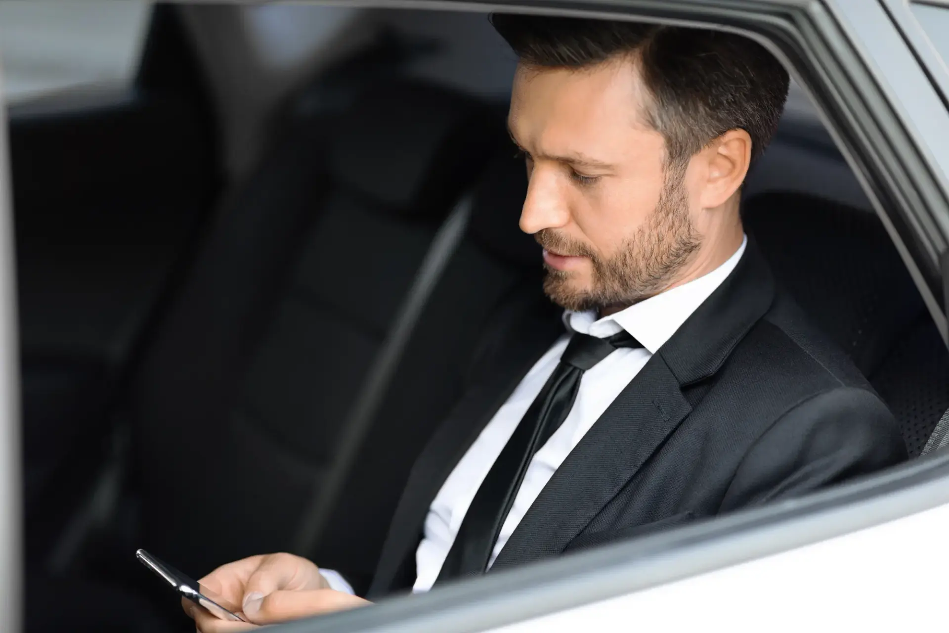 Passager en costume consultant son téléphone à l'arrière d'une berline